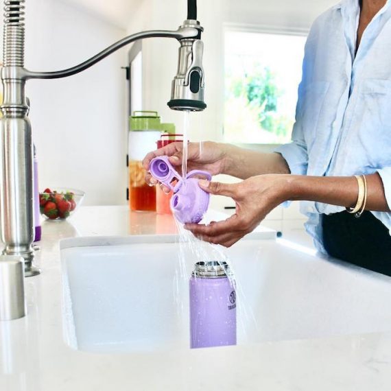 Woman at a sink washing a reusable water bottle. SourceL TakeyaUSA.com.