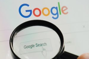 Google logo behind a magnifying glass