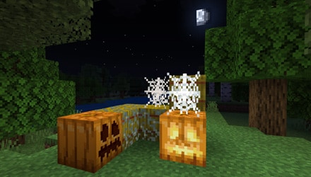 Image of jack=o-lanterns from Minecraft with some cobwebs on the grass in the dark