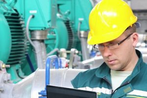 Photo of an industrial worker beside factory equipment