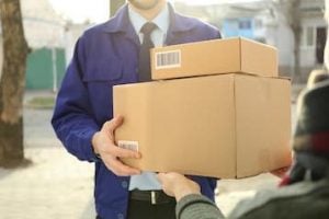 Photo of a delivery driver with a box at a front door