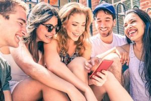 Happy multiracial friends having fun with a smartphone