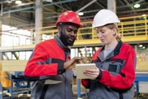 Male and female looking at a computer tablet in a factory