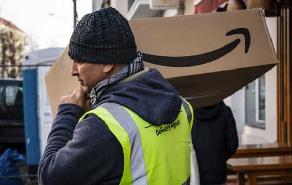 Delivery man carrying an Amazon box