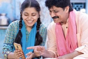 Photo of an Indian man and teenage daughter looking at a smartphone