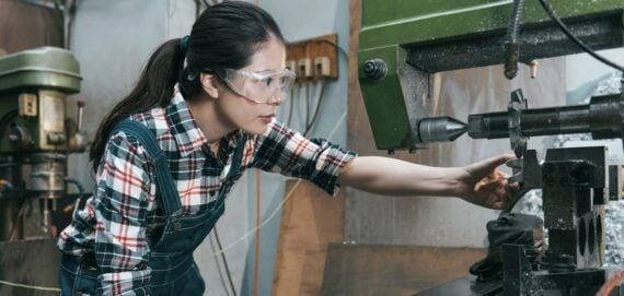 Female factory worker operating a machine