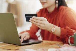 Female holding a credit card in front of a laptop