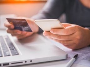 Photo of a person holding a credit card above a keyboard