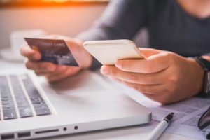 Photo of a person holding a credit card above a keyboard