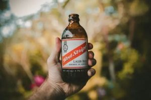 Image of a hand holding a Red Stripe lager beer. By Jakob Owens.