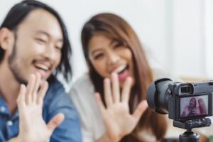 Photo of male and female in front of a camera selling merchandise