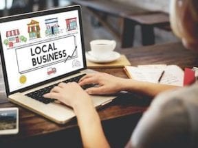 Photo a a lady typing on a laptop screen that says "Shop local"