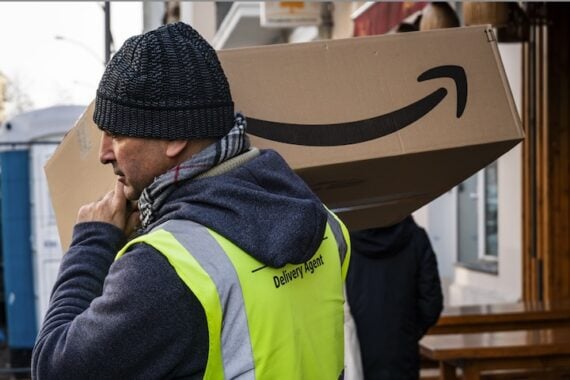 Photo of delivery male carrying an Amazon box