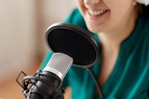 woman with microphone recording podcast at studio