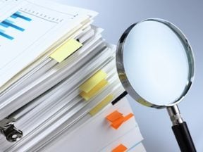 Stack of documents next to a magnifying glass